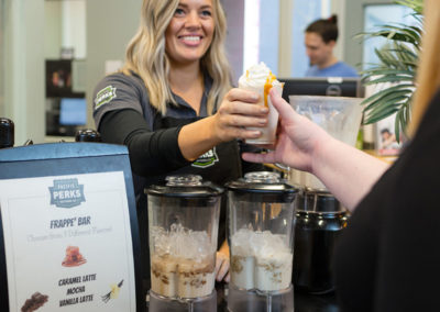 a Pacific Perks Perkologist handing a person a frappé drink during an event