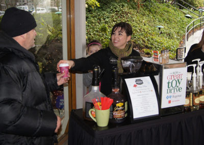 Natalie handing a drink to a guest at an outdoor Pacific Perks espresso bar