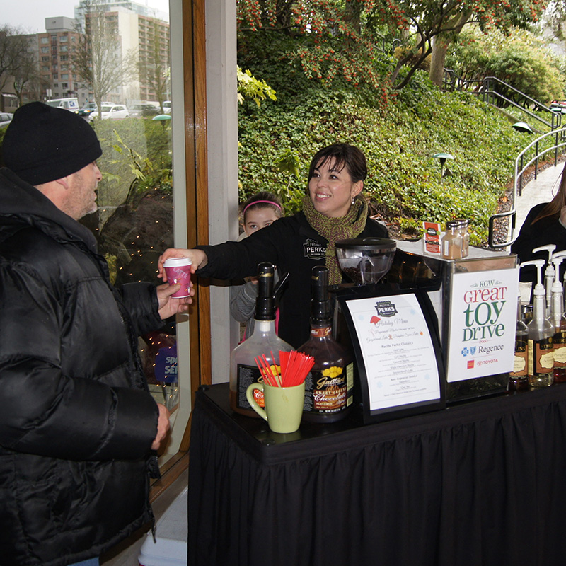 Natalie handing a drink to a guest at an outdoor Pacific Perks espresso bar