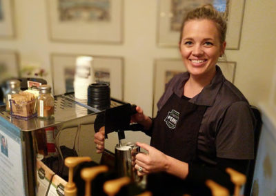 a Perkologist smiling while foaming milk at a Pacific Perks espresso mobile café