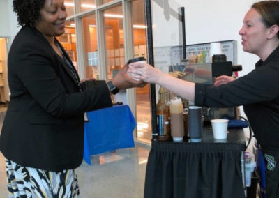a Pacific Perks Perkologist hands a guest an espresso during a Clark College Event