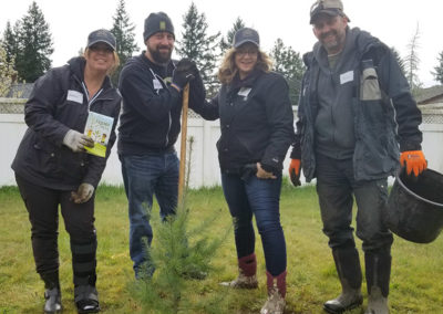 The Pacific Perks team posing next to a recently planted tree during a Friends of Trees event