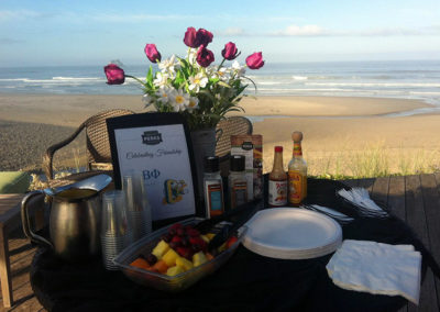 a serving table with flowers at a Pi Phi beach event hosted by Pacific Perks