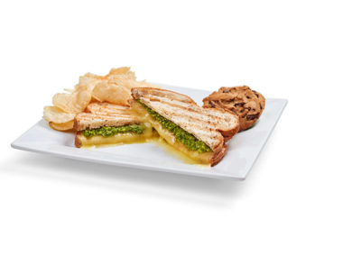 a plated "Pesto Don't Preach" grilled cheese with chips and a cookie sandwich from Pacific Perks