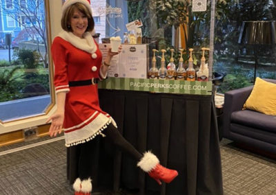 Laural Porter poses in a Santa outfit in front of a Pacific Perks espresso mobile café at a KGW event
