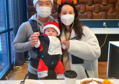 two parents holding their baby while sitting at a table with Pacific Perks waffles during a Nexus Orenco Station Christmas event