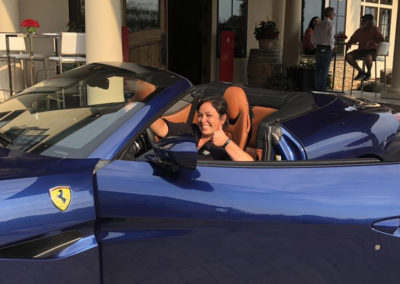 a Perkologist gives a thumbs up while sitting behind the wheel of a blue ferrari