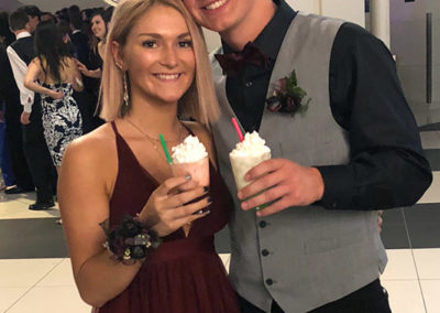 a couple in formal dress at a school prom smile with their drinks from a Pacific Perks espresso mobile café
