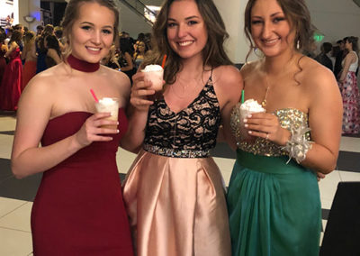 a group wearing dresses at a school prom event smile with their drinks from a Pacific Perks espresso mobile café