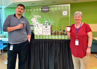 a pair posing with their Pacific Perks espresso drinks during a Spectrum event
