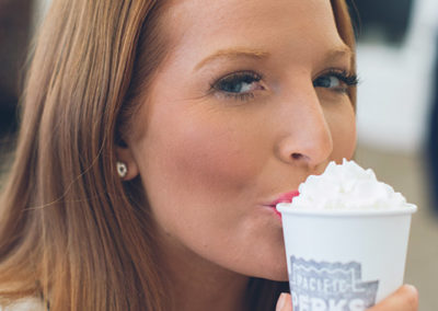 closeup of a woman sipping her Pacific Perks coffee drink