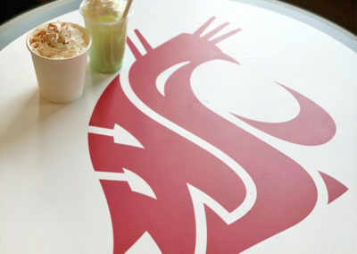 a Pacific Perks espresso drink and green smoothie sit on a circular table with the WSU Cougars logo