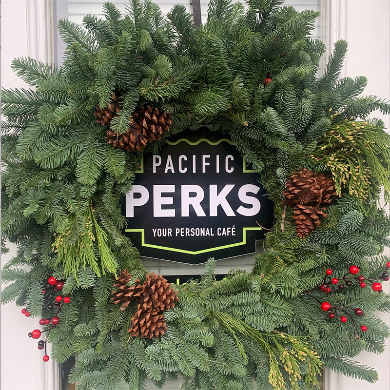 a wreath on a door with the Pacific Perks logo in the center