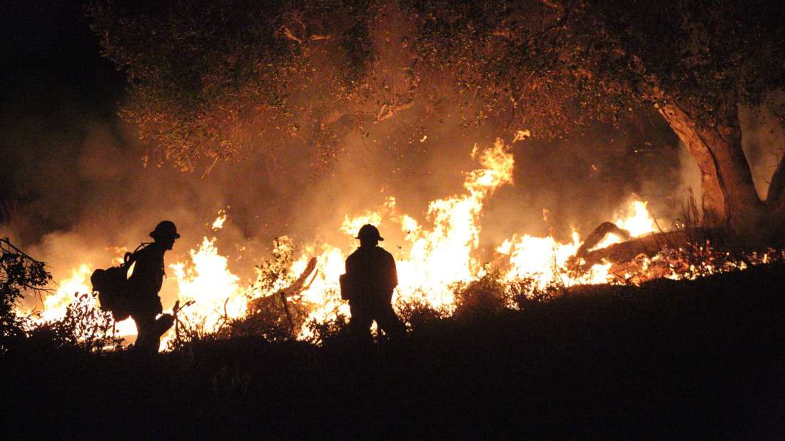 firefighters in front of a wildfire
