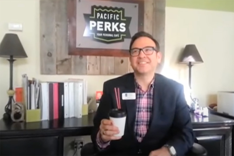 Eddie Allen holding a Pacific Perks coffee after The Gardner School of Arts and Sciences received a You've Been Perked event