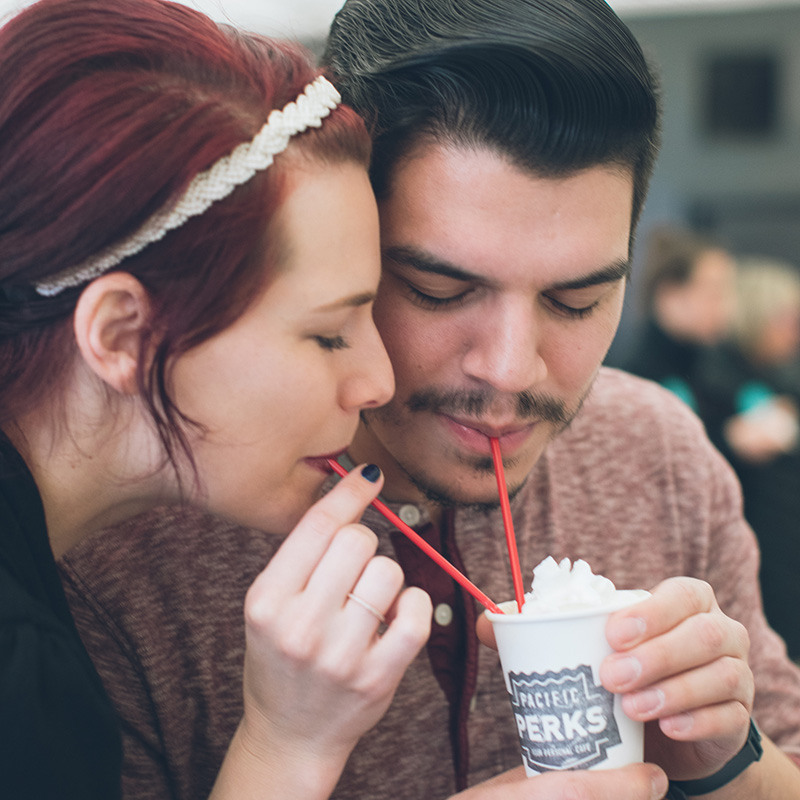 a couple sipping through straws to share a drink from a Pacific Perks mobile café