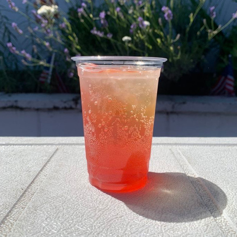 an italian soda from Pacific Perks sitting outdoors with lavender behind it