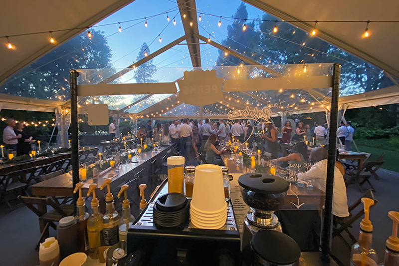 a Pacific Perks Coffee espresso bar mobile café inside a large tent at dusk during a wedding reception