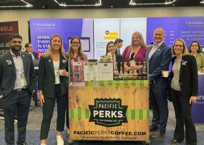 a group posing at a Pacific Perks espresso bar mobile café set up at a trade show